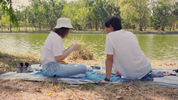 personas concepto de actividad con pareja asiática relajarse con la sensación de felicidad al lado del lago - Metraje, vídeo
