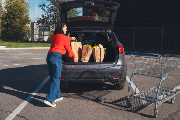 mulher colocar pacotes no carro compras de mantimentos tronco - Foto, Imagem