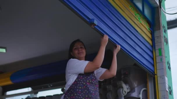 Imprenditrice del negozio di marciapiedi locale Proteggere Storefront chiudendo Garage Facciata - Filmati, video