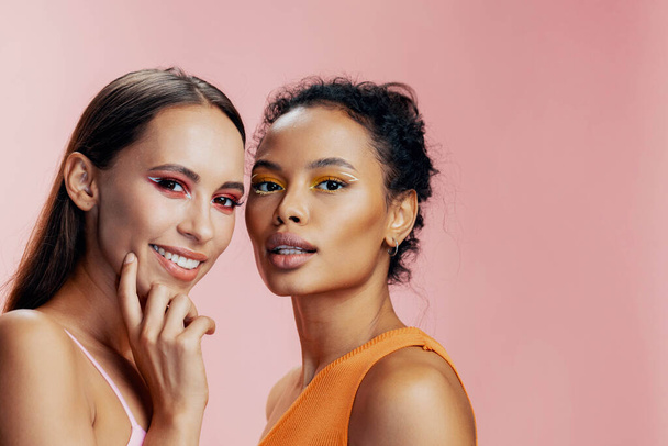 Жінка дві здорові красиві макіяж обличчя разом рожева раса африканські привабливі дівчата щасливі сяють барвисті змішані американські красиві моделі догляду за тілом студії портрет - Фото, зображення