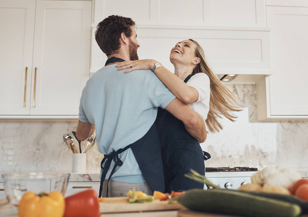 Főzés, tánc vagy boldog pár ünneplés az élelmiszer az egészséges vegán étrend együtt otthon. Ölelés, zöldségek vagy izgatott nő kötés a konyhában vacsorára szeretettel, mosollyal vagy romantikus férfi. - Fotó, kép