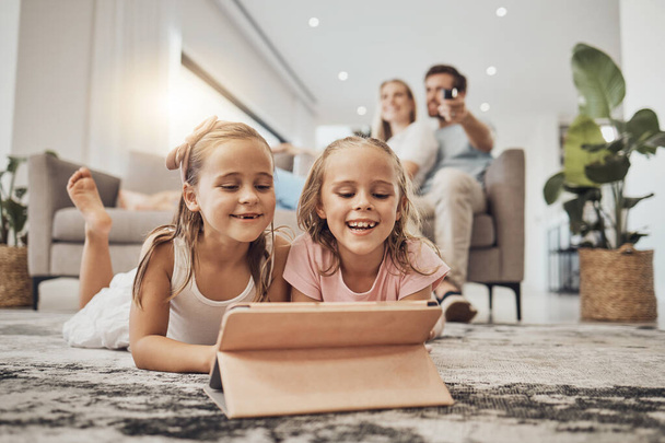 Children, tablet and relax on carpet for home learning, watch video and happy games with parents in living room. Girl or sister on digital technology for virtual school, family movie or film on floor. - Photo, Image