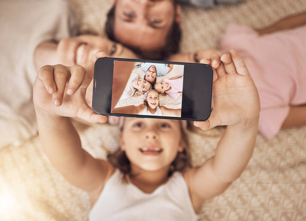 Telefon, Selfie und Familienbild auf einem Fußboden mit Liebe, Spaß und Lächeln für Social-Media-Posts zu Hause. Smartphone, Profilbild und Kindermädchen mit Eltern im Wohnzimmer fürs Wochenende. - Foto, Bild