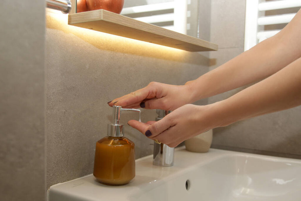 Γυναίκα πλύσιμο των χεριών με σαπούνι κάτω από το νερό στο νεροχύτη μπάνιο - Φωτογραφία, εικόνα