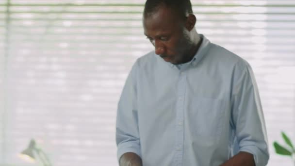 Αφρο-Αμερικανός υπάλληλος γραφείου πακετάρει τα υπάρχοντά του στο κουτί ενώ ετοιμάζεται να φύγει από το χώρο εργασίας μετά την απόλυσή του - Πλάνα, βίντεο
