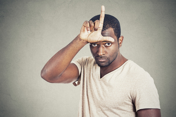 man showing loser sign on forehead looking at you - Photo, image