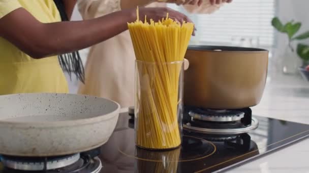 Приглушений знімок молодих багатоетнічних дівчат, які готують макарони на вечерю, збираючись вдома - Кадри, відео