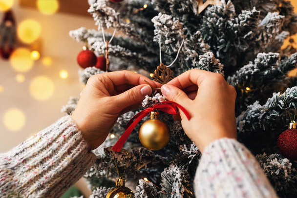 Διακόσμηση του χριστουγεννιάτικου δέντρου. Χριστουγεννιάτικο δέντρο διακόσμηση σε θηλυκά χέρια κοντά. - Φωτογραφία, εικόνα