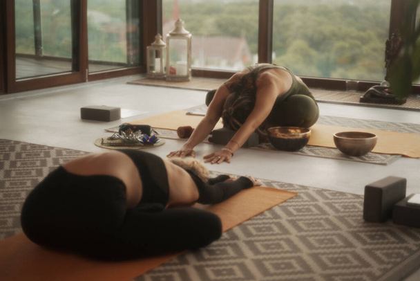 Grupo de chicas practicando yoga y meditación en un apartamento de la ciudad con vistas panorámicas - Foto, imagen