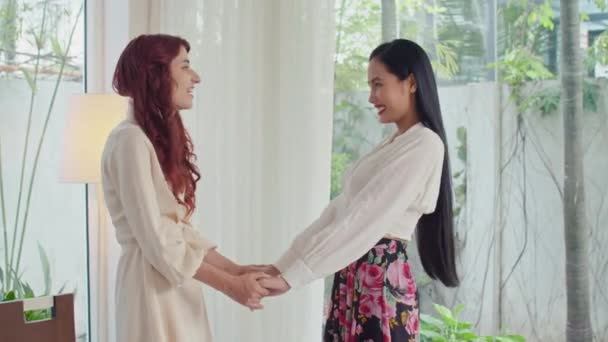 Medium lange schot van vrolijke multi-etnische vrouwelijke vrienden begroeten elkaar tijdens het verzamelen thuis - Video