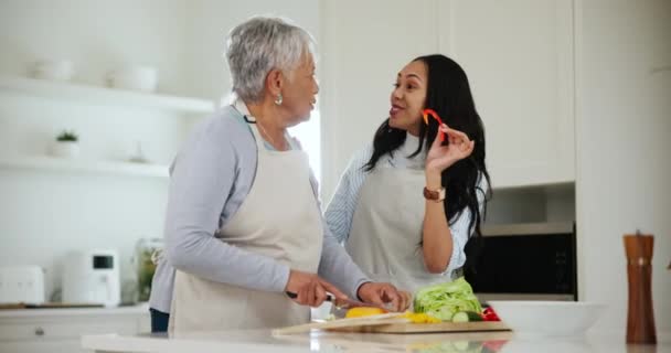 Οικογένεια, μαγείρεμα ή τοστ με μια ηλικιωμένη γυναίκα και κόρη στην κουζίνα ενός σπιτιού κατά τη διάρκεια μιας επίσκεψης. Φαγητό, χαμόγελο ή ευτυχία και ένα νεαρό άτομο να γελάει με την ηλικιωμένη μητέρα του σε ένα σπίτι για να ετοιμάσει ένα γεύμα. - Πλάνα, βίντεο