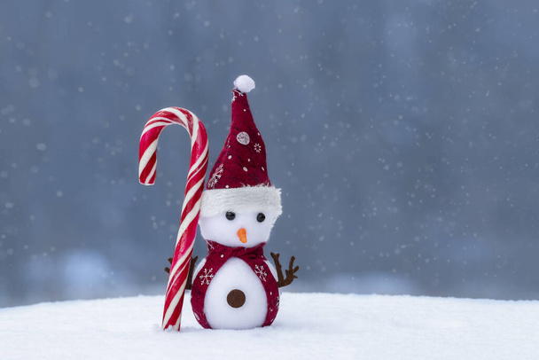 Weihnachtskomposition mit einem Spielzeug-Schneemann auf schneebedecktem Hintergrund. Urlaubskonzept für Neujahrskarten. - Foto, Bild