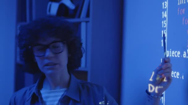 Detailní záběr ženského bělošského učitele stojícího před projekcí obrazovky vysvětlujícího kód v tmavé třídě s modrým světlem - Záběry, video