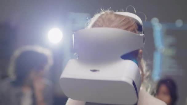 Primer plano de la chica de edad elemental con gafas VR y sosteniendo sensores en las manos moviéndolos hacia arriba y hacia abajo haciendo algo en el espacio virtual - Metraje, vídeo
