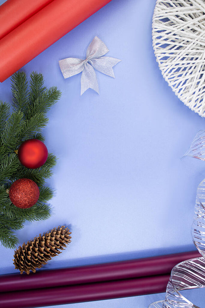 Geschenkrollen aus Papier, Tannenzapfen, Schleife und Schleife, Tannenzweige mit Weihnachtskugeln auf blauem Hintergrund. Weihnachten im neuen Jahr. Zubehör für Geschenkverpackung - Foto, Bild