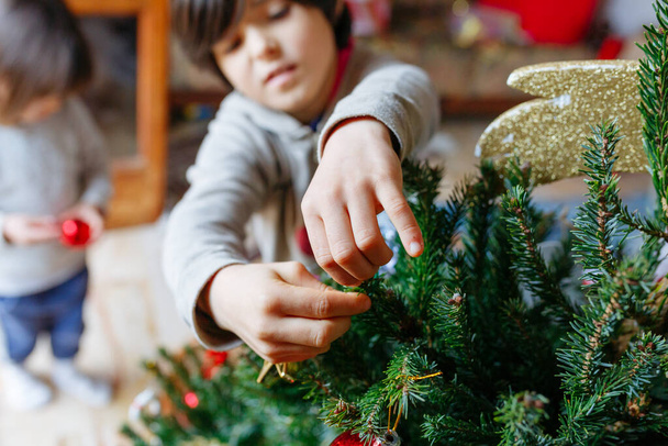 magas szög kilátás a kezét a gyermek, aki üzembe dekoráció zöld karácsonyfa - Fotó, kép