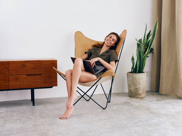 Menina estudante educação sentado em uma cadeira com um laptop trabalhar em casa sorrir e relaxar, moderno estilo de vida escandinavo interior elegante, espaço de cópia. Foto de alta qualidade - Foto, Imagem