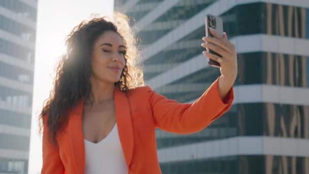 ハッピーなバイの人種多様な女性は,セルフィーを服用し,セルフィーを服用し,キスを吹き飛ばし,サンセットでソーシャルメディアに投稿します. ファッションライフスタイルインフルエンサー 映画の太陽レンズフレアでモバイルスマートフォンを使用してブロガー - 映像、動画