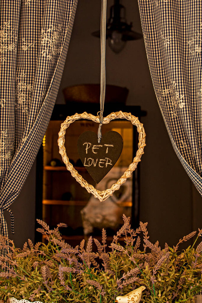 симпатичное плетеное сердце с деревянным сердцем внутри с посланием о любви к животным на окне. Уход за животными - Фото, изображение