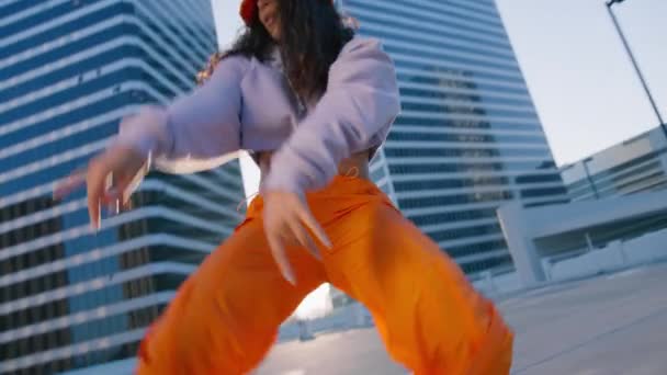 Seksi Twerk ve serbest stil dansçısı şehrin arka planında altın günbatımında dans figürleri yapıyor. Afrikalı Amerikalı genç bir kadın çatıda şehvetle dans ediyor. - Video, Çekim