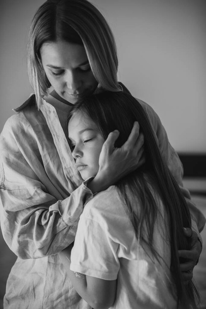 Festa della mamma. Una figlioletta abbraccia amorevolmente sua madre. BW foto. - Foto, immagini