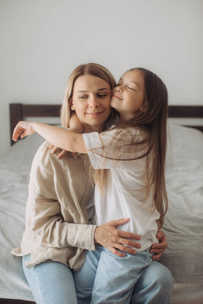 Muttertag. Eine kleine Tochter umarmt ihre Mutter liebevoll. - Foto, Bild