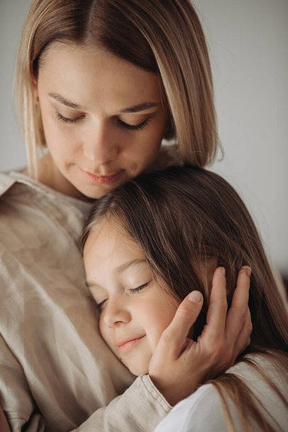 Moederdag. Een dochtertje knuffelt liefdevol haar moeder. - Foto, afbeelding