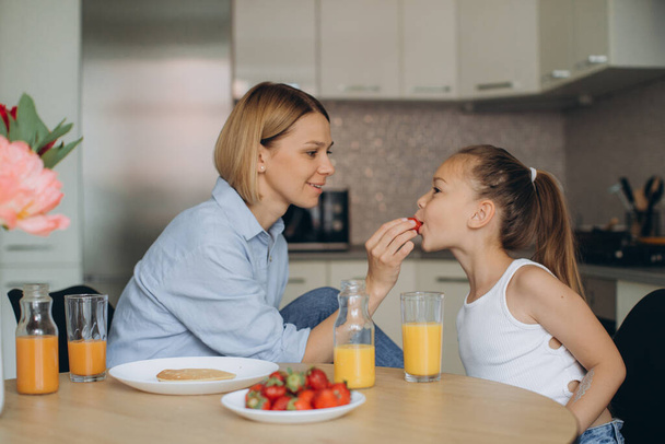 Lifestyle-Foto von Mutter und kleiner Tochter beim gemeinsamen Frühstück. Viel Spaß bei der gemeinsamen Zeit zu Hause. - Foto, Bild