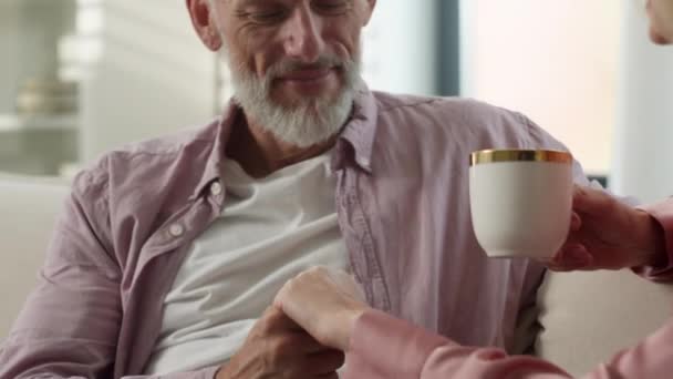 Rakastava huolehtiva hellä vanhukset valkoihoinen mies suudella käsi rakastettu vaimo nainen juo aromaattista kahvia nauttia tarjouksen romanttinen rakkaus hetki onnellinen aviopari liimaus yhdessä kotona - Materiaali, video