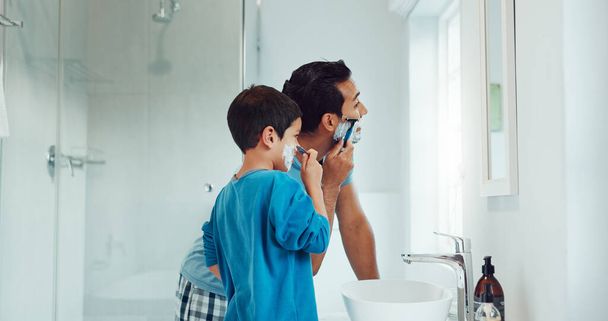 Papa, Junge und lernen, sich im Badezimmer mit Gesichtscreme, Hautpflege und Unterstützung zu rasieren. Vater, Kind und Unterricht in Kosmetik für Gesicht, Bart und Schaum für Liebe, Pflege und Familie zu Hause. - Foto, Bild
