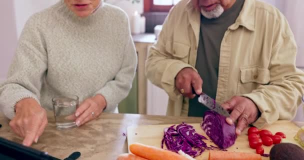 Kochen, unterstützen oder alte Paare mit Tabletten oder Lebensmitteln für eine gesunde Ernährung gemeinsam im Ruhestand zu Hause. Lernende, interrassische oder glückliche Seniorin in der Küche im Gespräch mit einem reifen Mann zum Abendessen Rezept. - Filmmaterial, Video