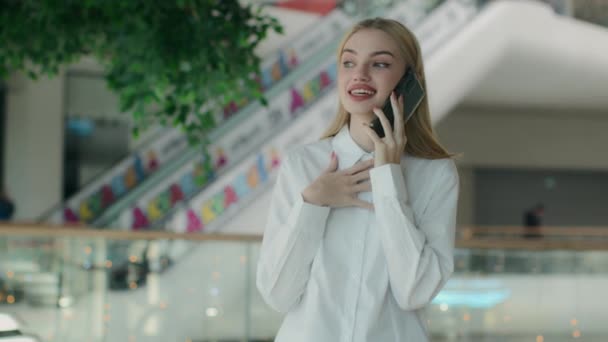 Счастливая деловая девушка молодая деловая женщина говорить смартфон звонок в торговом центре говорить дружественный разговор мобильный телефон в помещении улыбается кавказская женщина приятный разговор обсудить хорошие новости - Кадры, видео