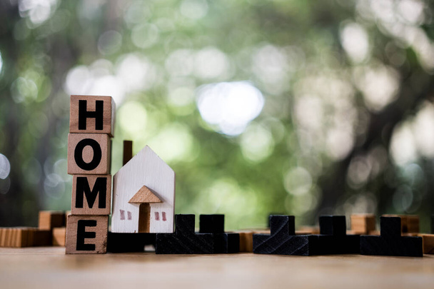 Ein Musterhaus-Modell mit Text von HOME wird auf Holztisch als Hintergrund Immobilien-Konzept mit Kopierraum für Ihren Text oder Design platziert. - Foto, Bild