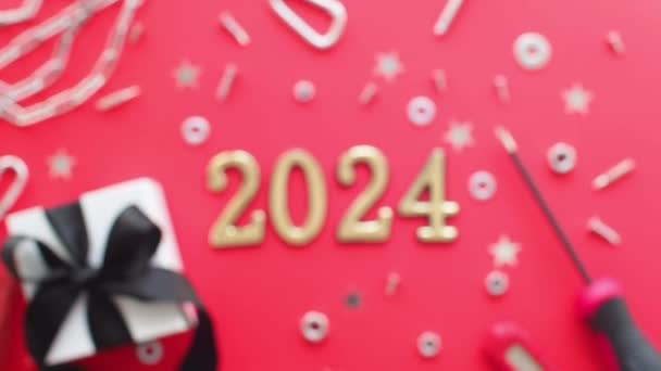 2024 und Bauwerkzeuge und verpacktes Geschenk auf rotem Hintergrund. Baugrußkarte für Weihnachten oder Neujahr. Zuhause reparieren. Geschenke für Männer. Geschenke für den Mann kaufen. - Filmmaterial, Video