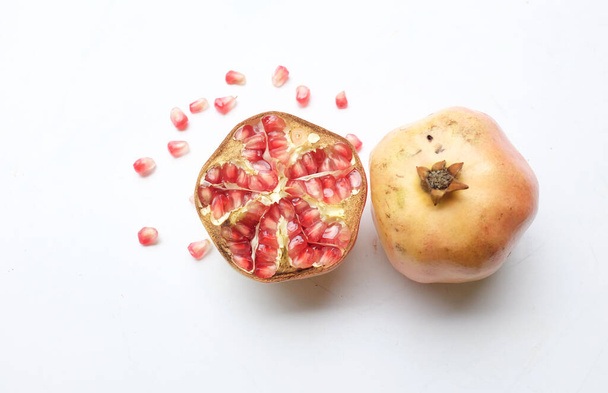 Nahaufnahme eines frischen reifen roten Granatapfels (punica granatum) mit halbiertem grünen Blatt isoliert auf weißem Hintergrund. - Foto, Bild