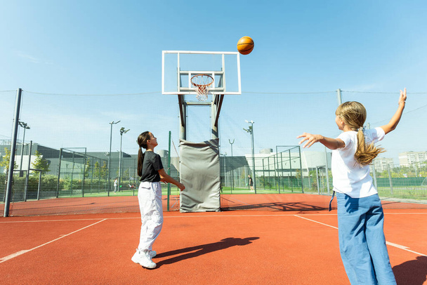Concept of sports, hobbies and healthy lifestyle. Young people playing basketball on playground outdoors. High quality photo - Photo, Image
