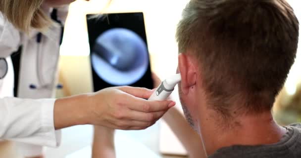 Otorinolaringoiatra esamina orecchio paziente utilizzando otoscopio digitale con immagine. Prova uditiva e infiammazione del timpano - Filmati, video