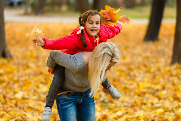 mother and daughter in the city park in autumn having fun time - Foto, Imagen