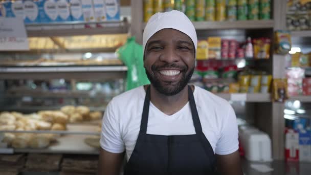 Ένα μαύρο αντρικό προσωπικό μπακάλικου πίσω από πάγκο χαμογελώντας. Πορτρέτο ενός χαρούμενου νεαρού Αφροαμερικανού υπαλλήλου στην καφετέρια - Πλάνα, βίντεο