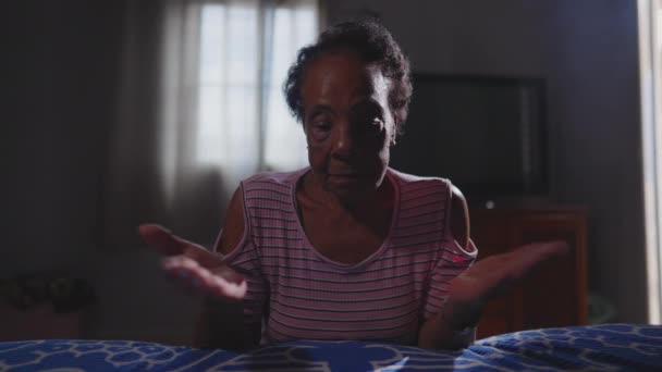 Eine spirituelle ältere schwarze Brasilianerin betet Gott im Gebet zu Hause am Krankenbett an. Religiöse ältere Dame bittet um Anleitung - Filmmaterial, Video