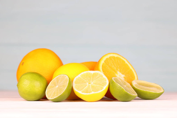 Orange Limetten und Zitrusfrüchte auf weißem Tisch und blauem Hintergrund in Nahaufnahme - Foto, Bild