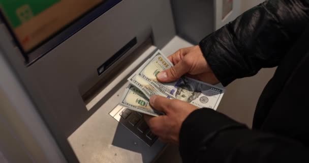 Mies laskee pankkiautomaatista nostetut dollarit. Vuorokausipalvelu. Käteisnostot ja pankkitoiminnot - Materiaali, video