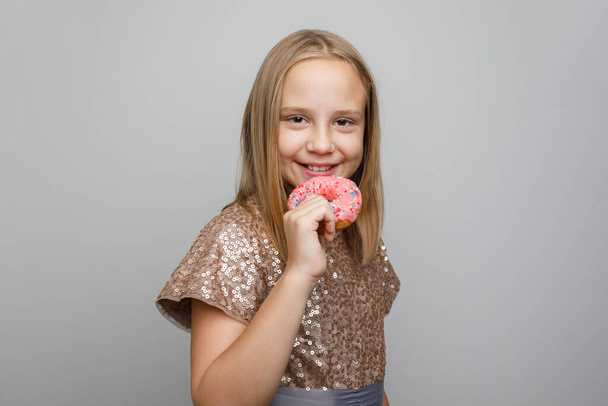 Rire enfant fille manger beignet rose vif debout contre fond gris bannière murale studio. Fête d'anniversaire concept - Photo, image