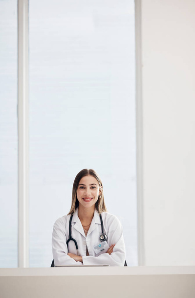 Portrait, doctor and space with a woman arms crossed in a hospital for healthcare, consulting or trust. Medical, smile and a happy young medicine professional at a desk in a clinic for cardiology. - Photo, Image