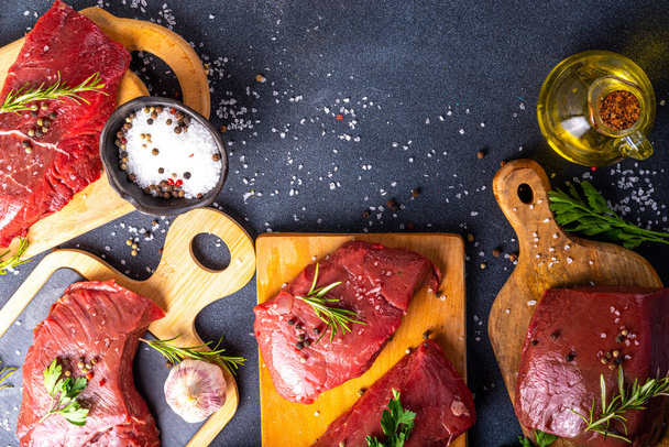 Cooking food background. Various cuts of raw fresh veal, beef, red meat with spices, rosemary, salt, pepper, garlic, olive oil, top view copy space - Photo, Image