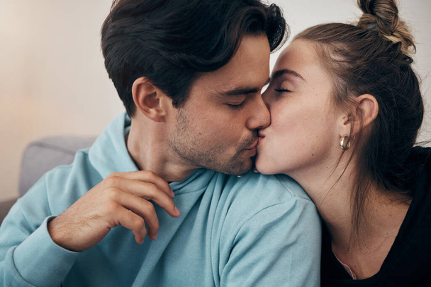 Couple, relax and kiss on sofa with love in home, living room or house with happy, partnership or marriage. Romantic, people and bonding with man and woman in affection for support and care together. - Photo, Image