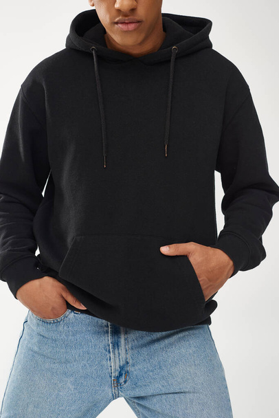 trendiges afrikanisch-amerikanisches Männermodel in lässigem schwarzen Kapuzenpulli und Jeans, Kopierfläche für Werbung - Foto, Bild