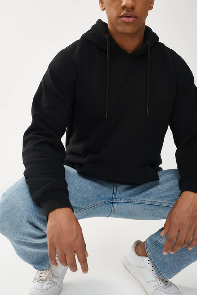 trendy Afro-Amerikaanse man model in casual zwarte hoodie en jeans, kopieer ruimte voor reclame - Foto, afbeelding