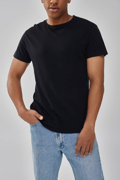 κομψό αφροαμερικάνικο ανδρικό μοντέλο ποζάρει σε μαύρο t-shirt και τζιν, φωτοτυπικός χώρος για διαφήμιση - Φωτογραφία, εικόνα