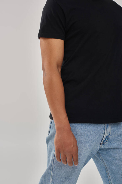 modelo masculino afroamericano elegante posando en camiseta negra y pantalones vaqueros, espacio de copia para la publicidad - Foto, imagen